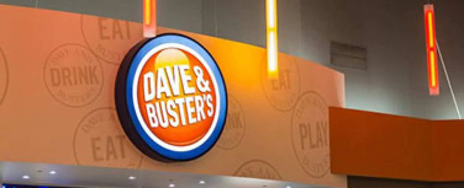 Dave & Buster's brightly lit sign above the entrance with colorful hanging lights in an entertainment venue.