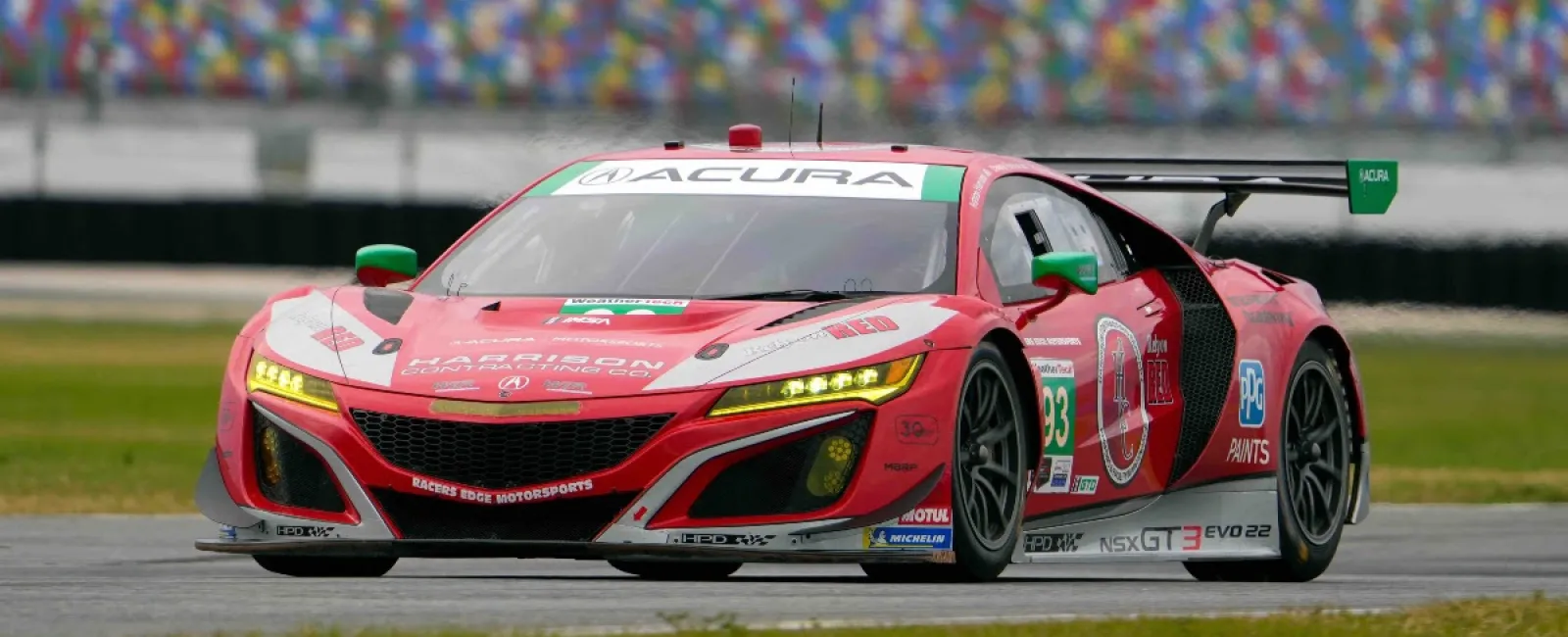 Red Acura NSX GT3 EVO22 race car with number 93 racing on a track at a motorsport event