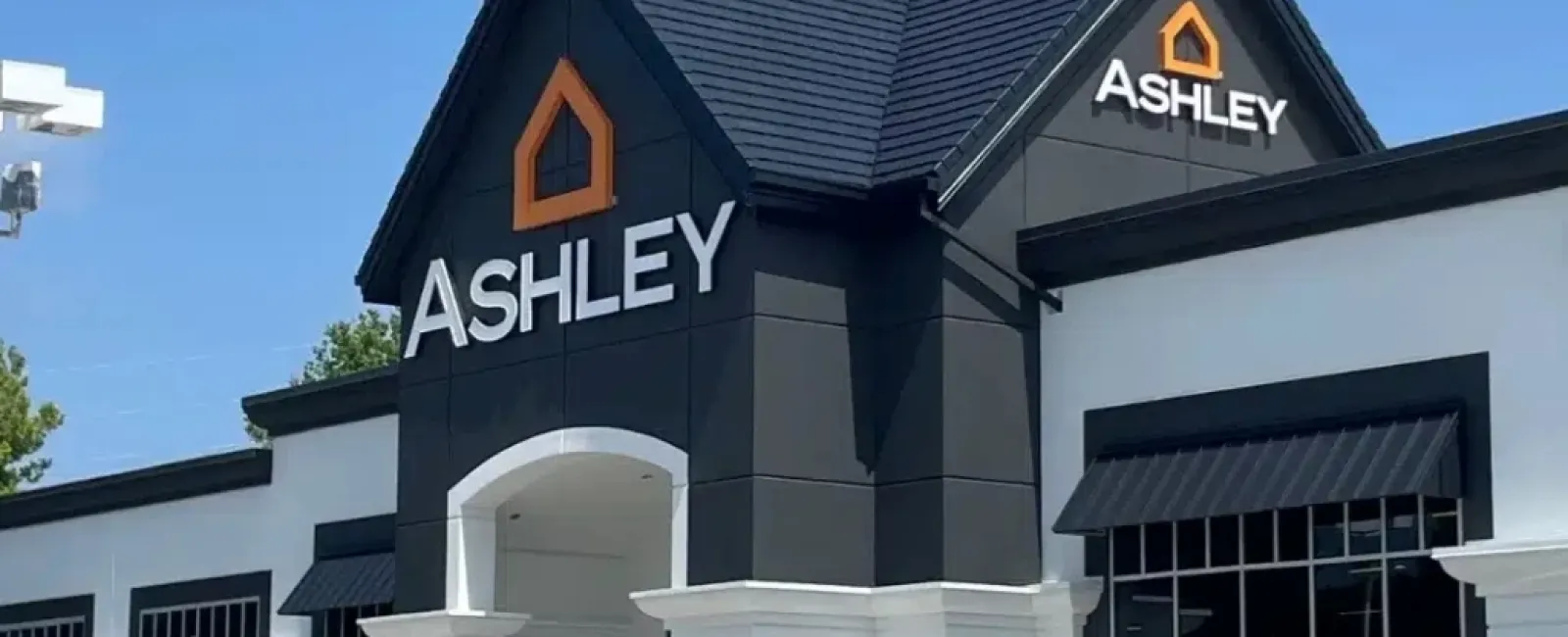 Modern Ashley Furniture store exterior with black and white design under clear blue sky