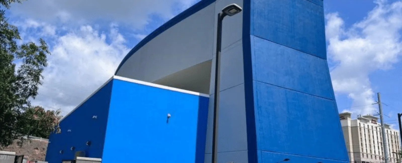 Modern building with bold blue and gray exterior under a partly cloudy sky.