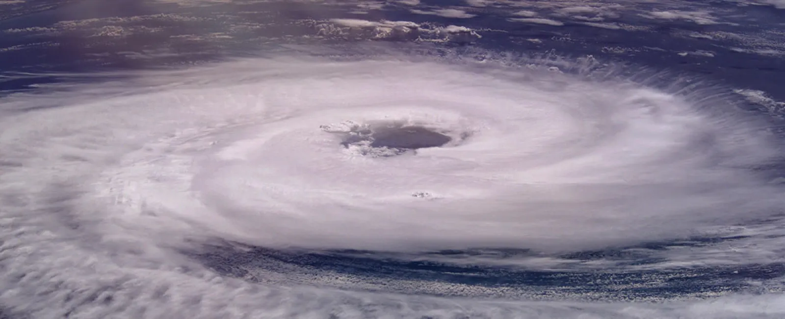 Satellite image of a massive hurricane with a clear eye over the ocean, showing swirl of dense clouds.