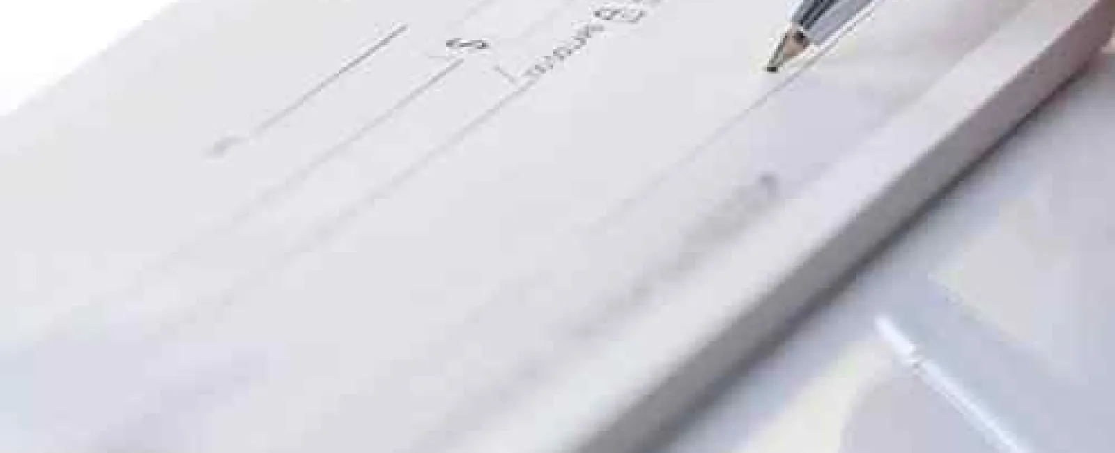 Close-up of a pen poised to write on a blank check lying on a reflective surface.