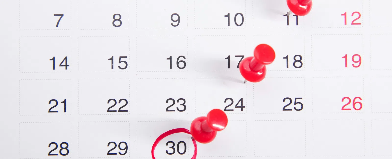 Calendar with red push pins marking dates and the 30th circled in red pen for emphasis.