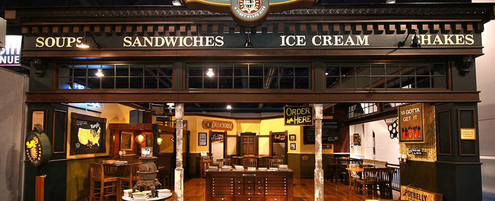 Potbelly Sandwich Works eatery interior with wooden floors, vintage decor, and menu signs for soups, sandwiches, ice cream, and shakes.