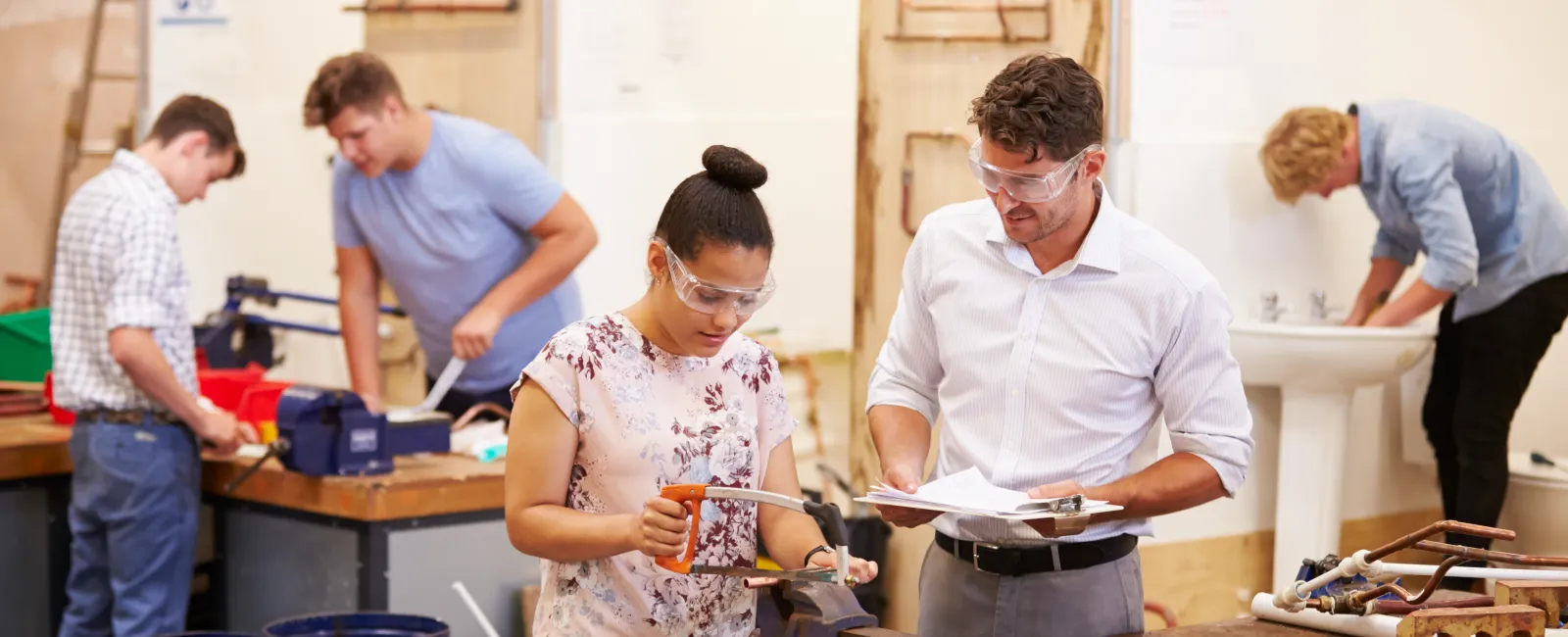 Students working on plumbing projects in a workshop, focusing on hands-on learning and collaboration.