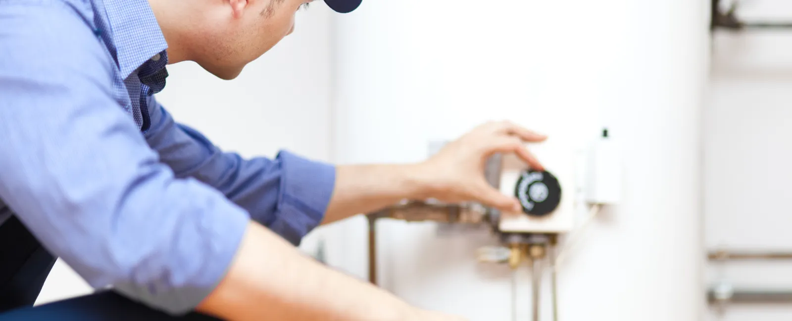 Technician adjusting a water heater's temperature in a residential setting for optimal performance.