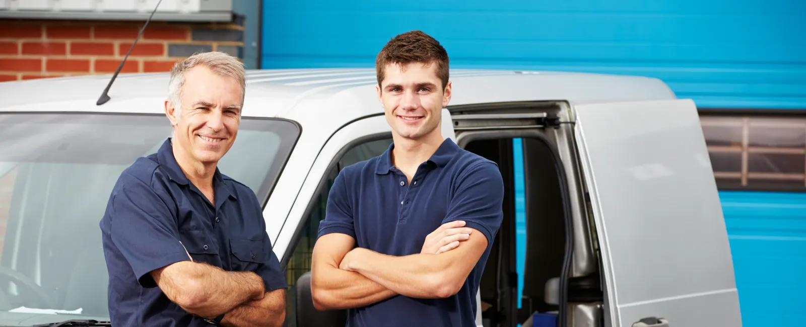 Two skilled tradesmen stand confidently by their service van, showcasing teamwork and professionalism.