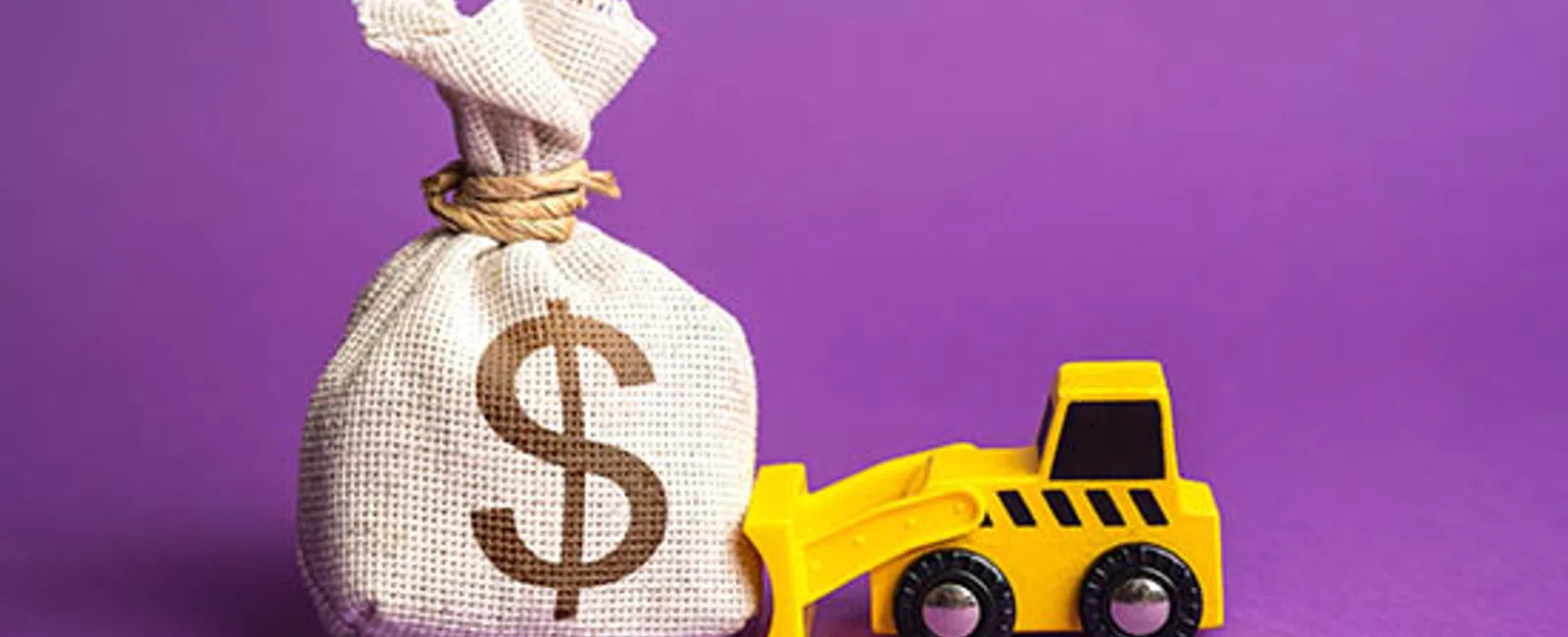 Yellow toy bulldozer pushing a burlap money bag with a dollar sign on a purple background