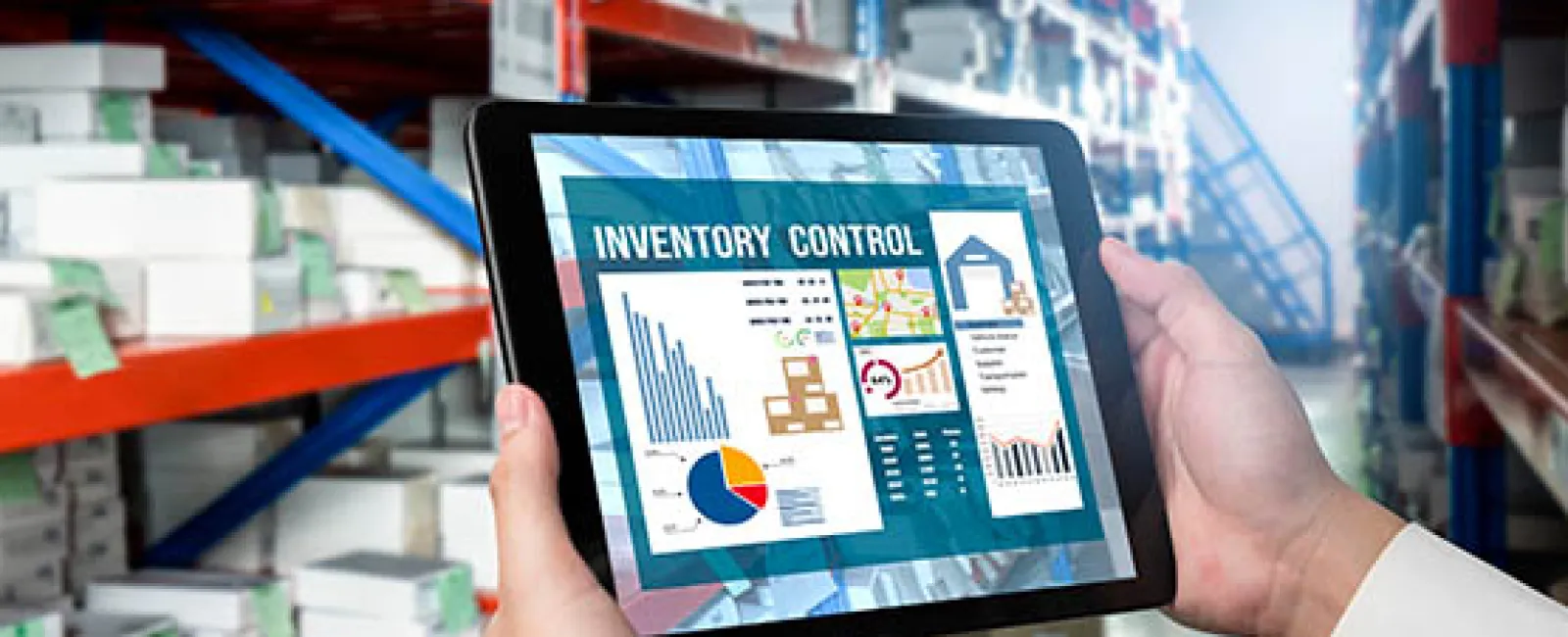 Person holding tablet displaying inventory control charts and graphs in a warehouse setting.