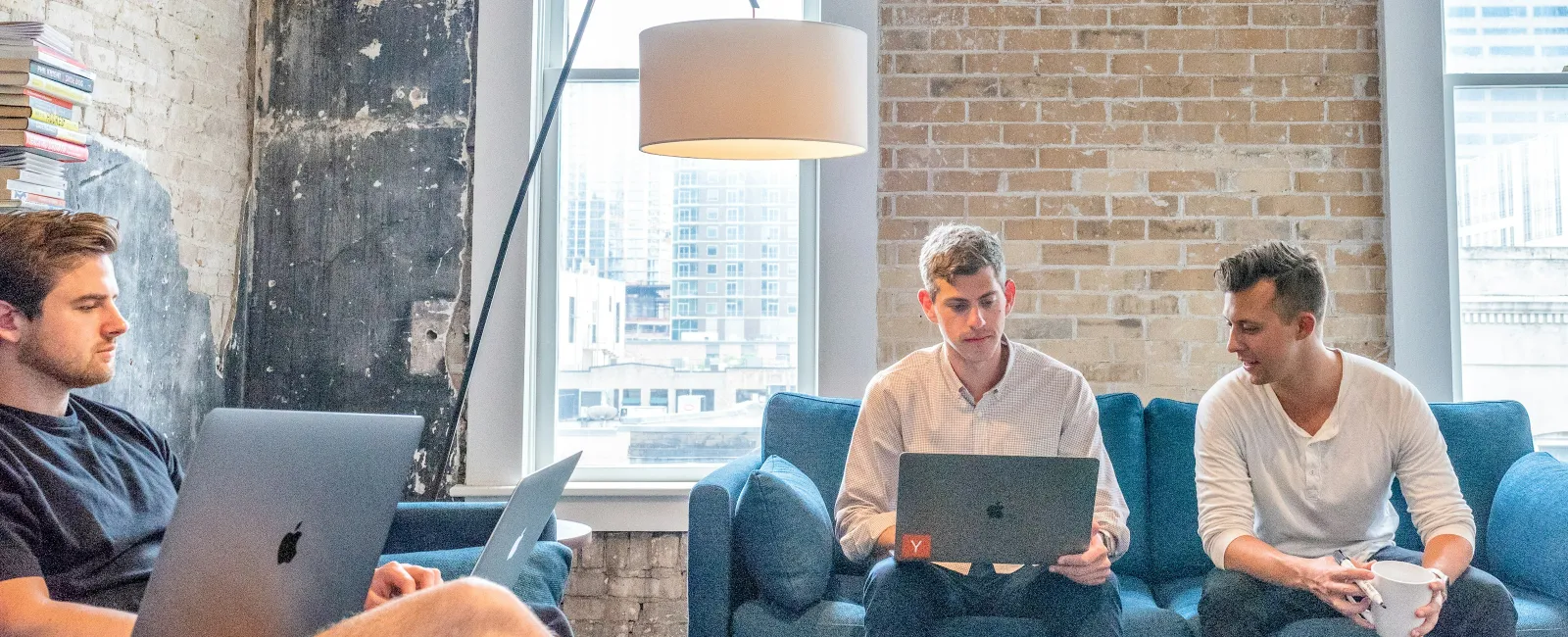 men sitting on a couch using laptops