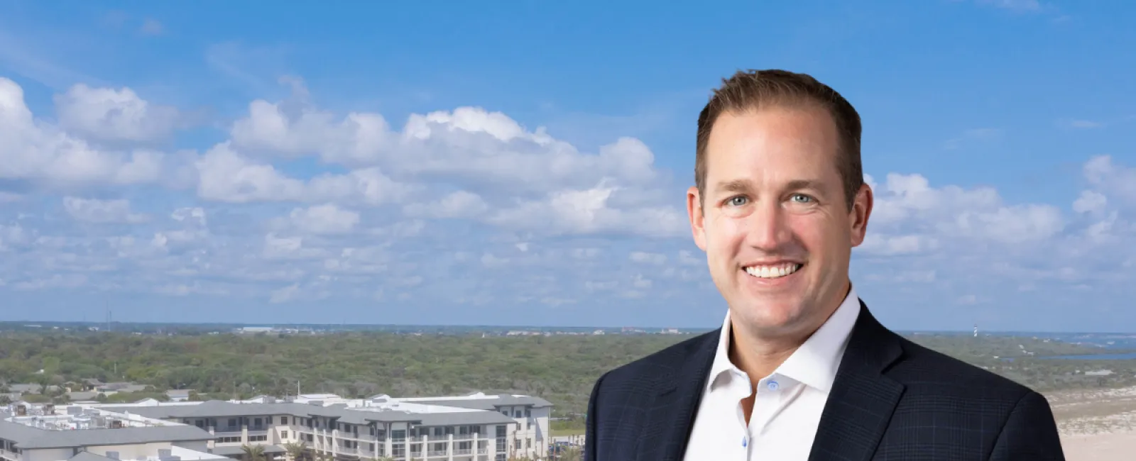 Smiling man in suit standing by beach resort with waves and text Deals Are Coming Back