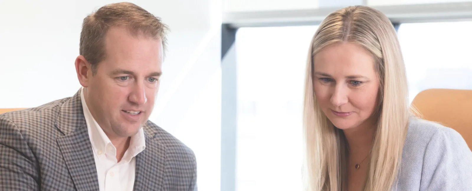 Two professionals discussing business strategy emphasizing relationships over rates in a modern office setting.