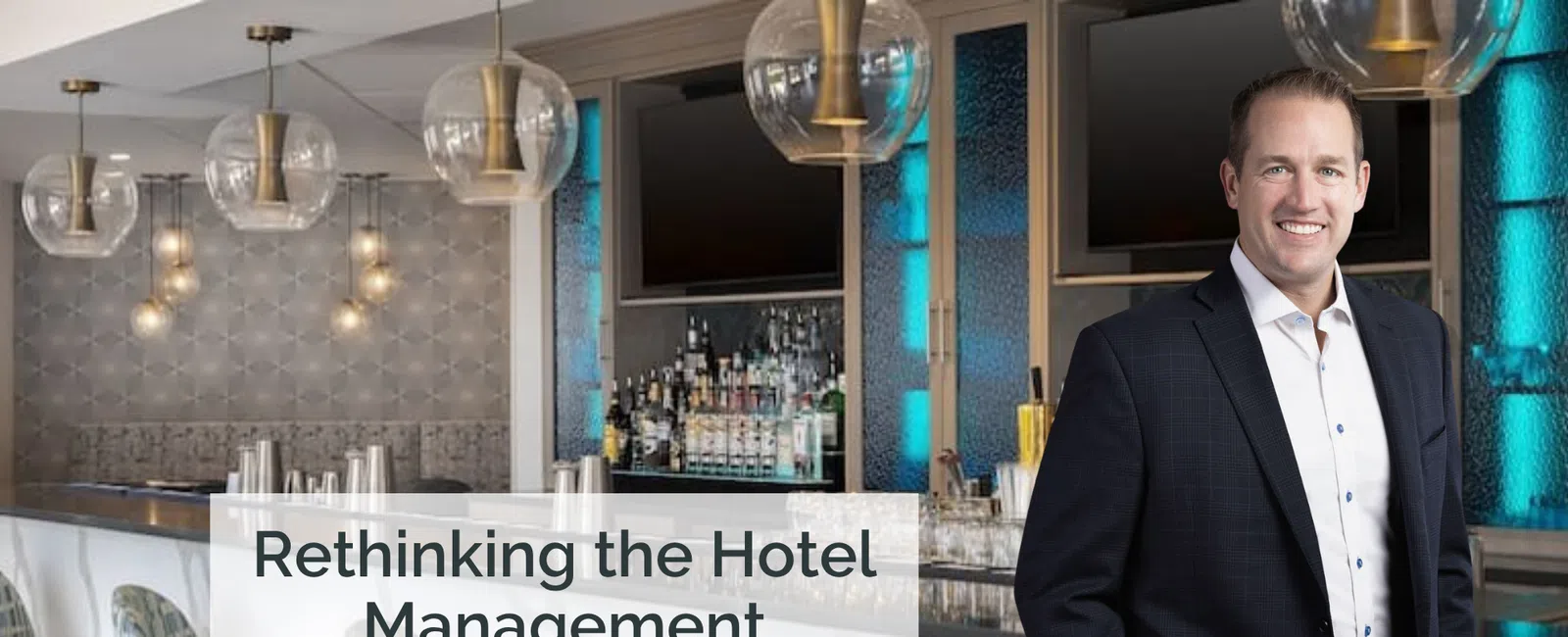 Man in blazer standing beside modern hotel bar with stools, glass lights, and backlit shelves.