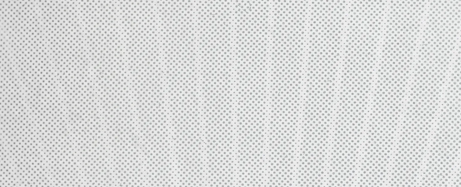 Close-up of a white textured surface with a pattern of evenly spaced small holes or dots.
