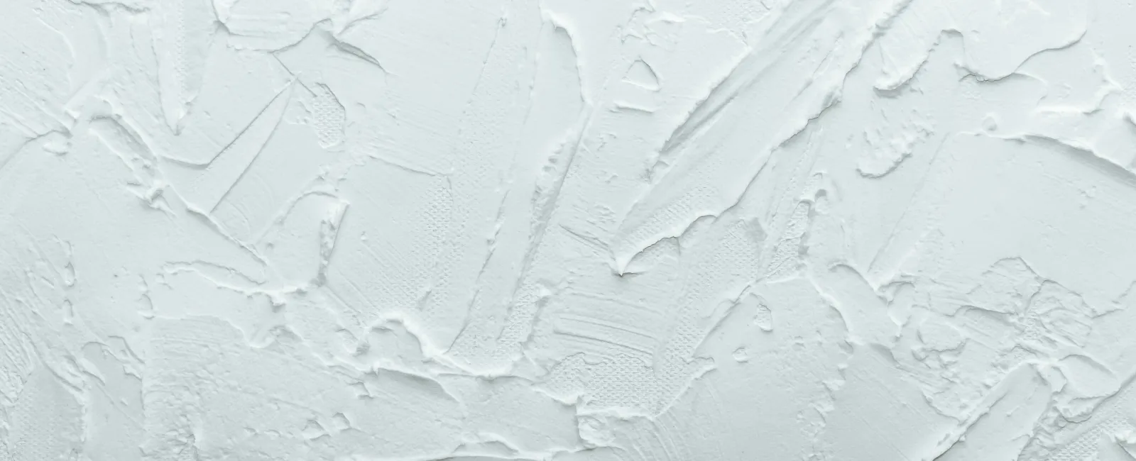 White textured plaster wall with rough, uneven patterns and brush strokes creating a 3D effect.