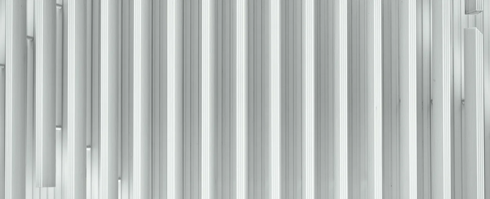 Abstract vertical white linear pattern with varying depths creating a textured wall effect.
