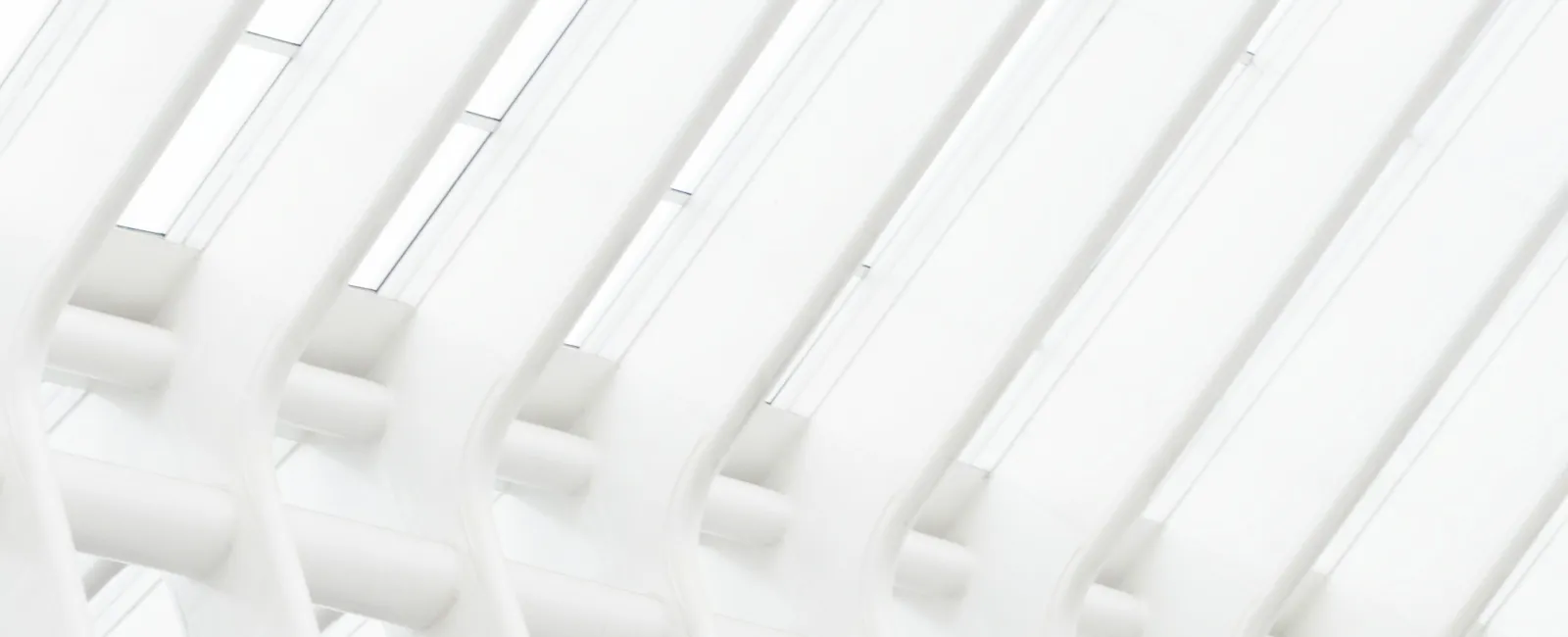 Modern architectural ceiling with repeating white ribs and skylights creating a bright geometric pattern