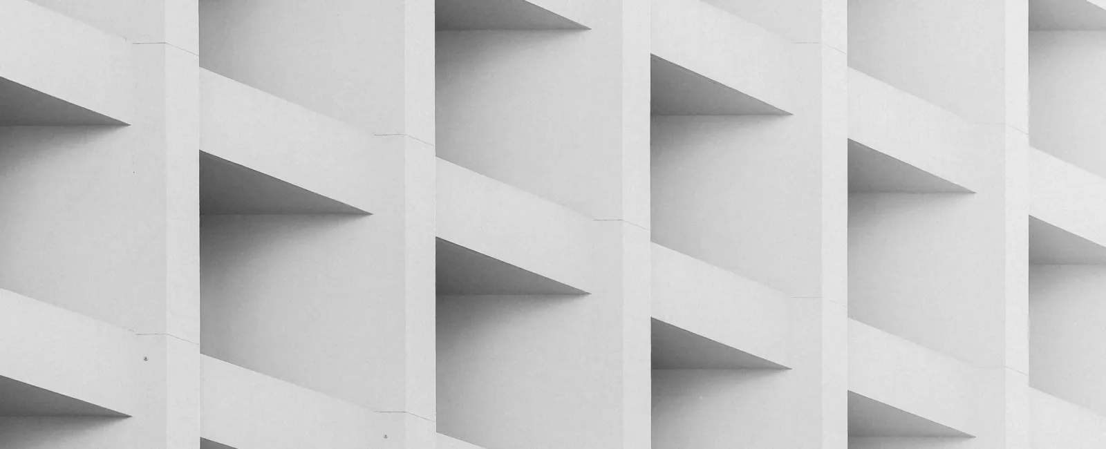Close-up of a modern building facade with repeating white concrete triangular balconies in a geometric pattern