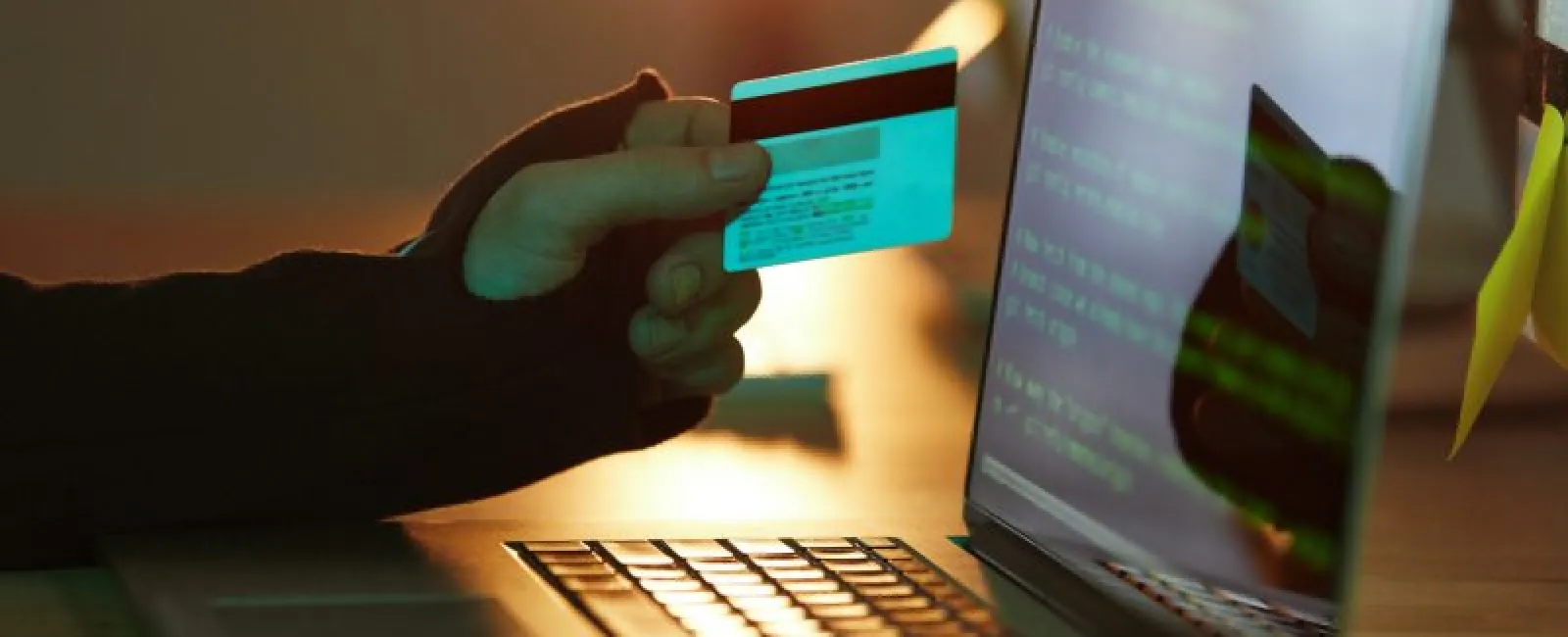 a hand holding a card over a laptop