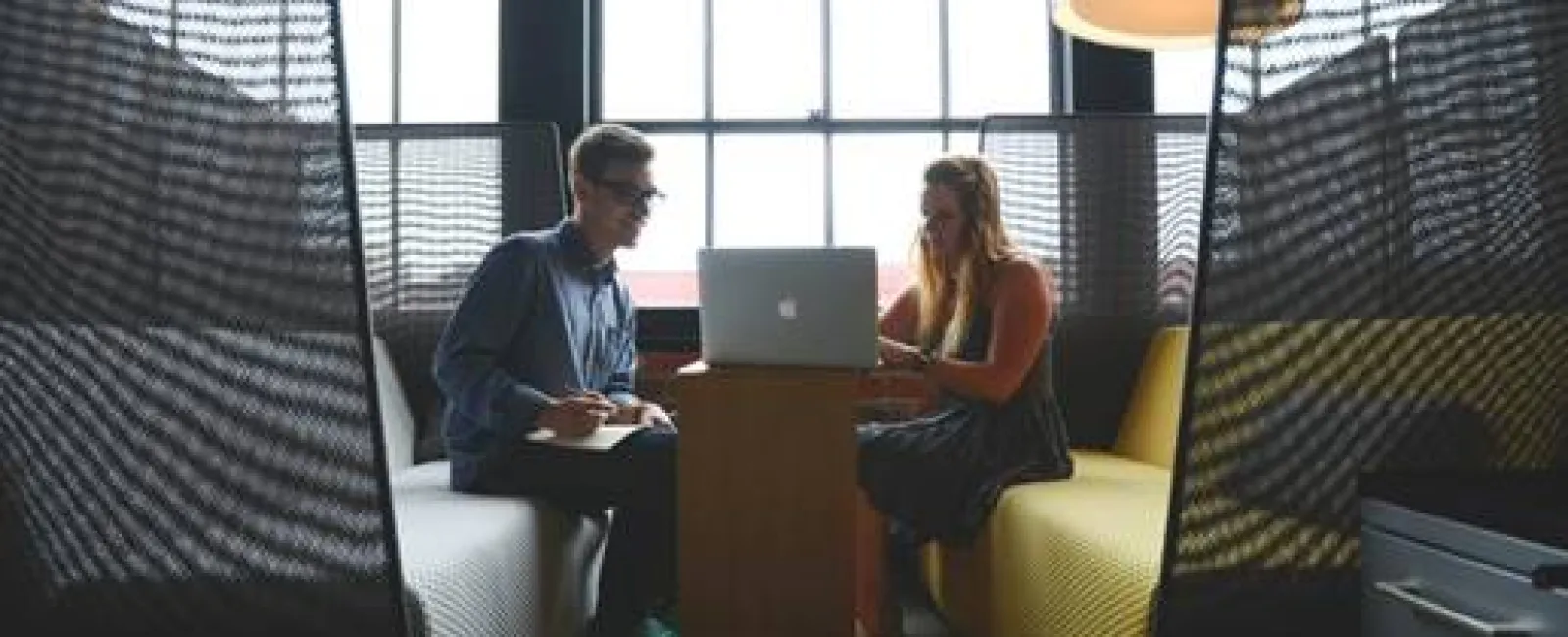 a man and a woman sitting at a table with a laptop