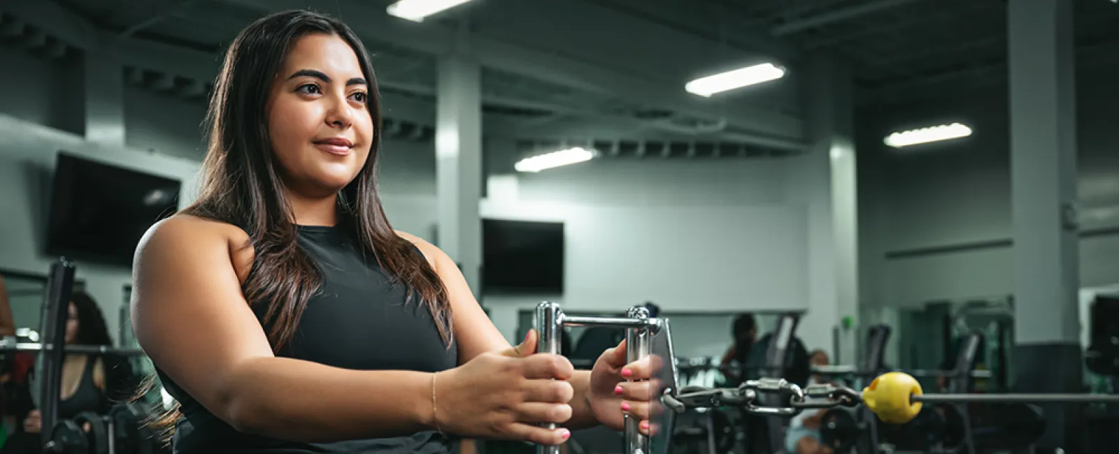 Woman using gym equipment for strength training in a modern fitness center.