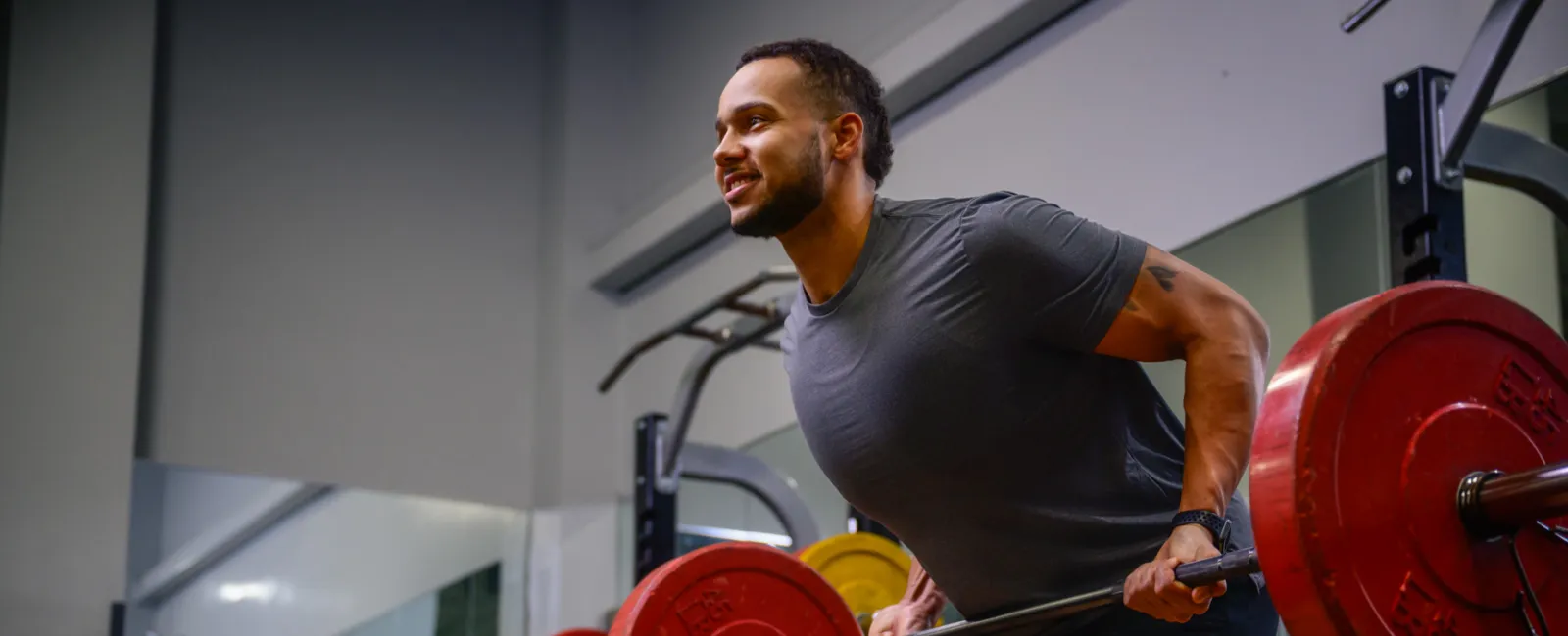 Man lifting a barbell with red weights in a gym, focused on strength training and fitness.