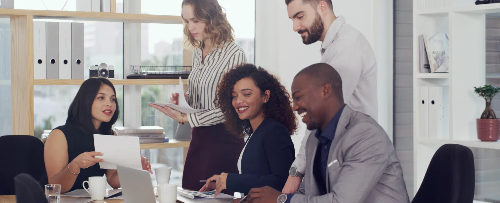 Diverse business team collaborating and discussing documents around a table in a modern office setting.