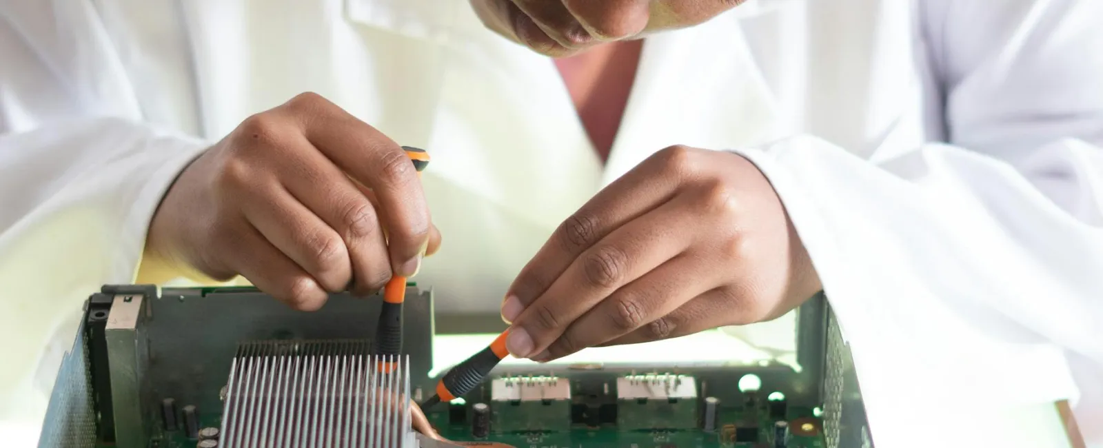 Technician carefully repairing or assembling electronic circuit board inside a computer with tools