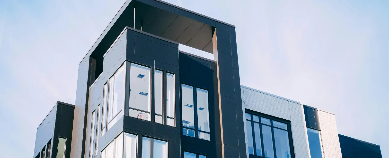 Modern black and white commercial building with large glass windows under a clear blue sky.