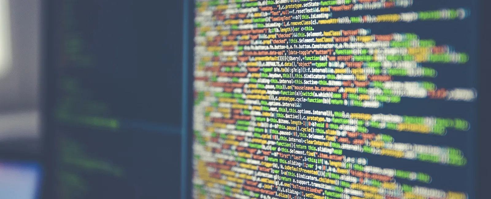 Close-up of colorful computer programming code displayed on a monitor with blurred background.