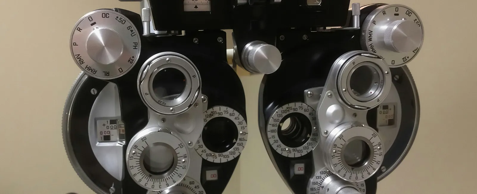 Close-up of a phoropter used in eye exams with multiple dials and lenses for vision testing.