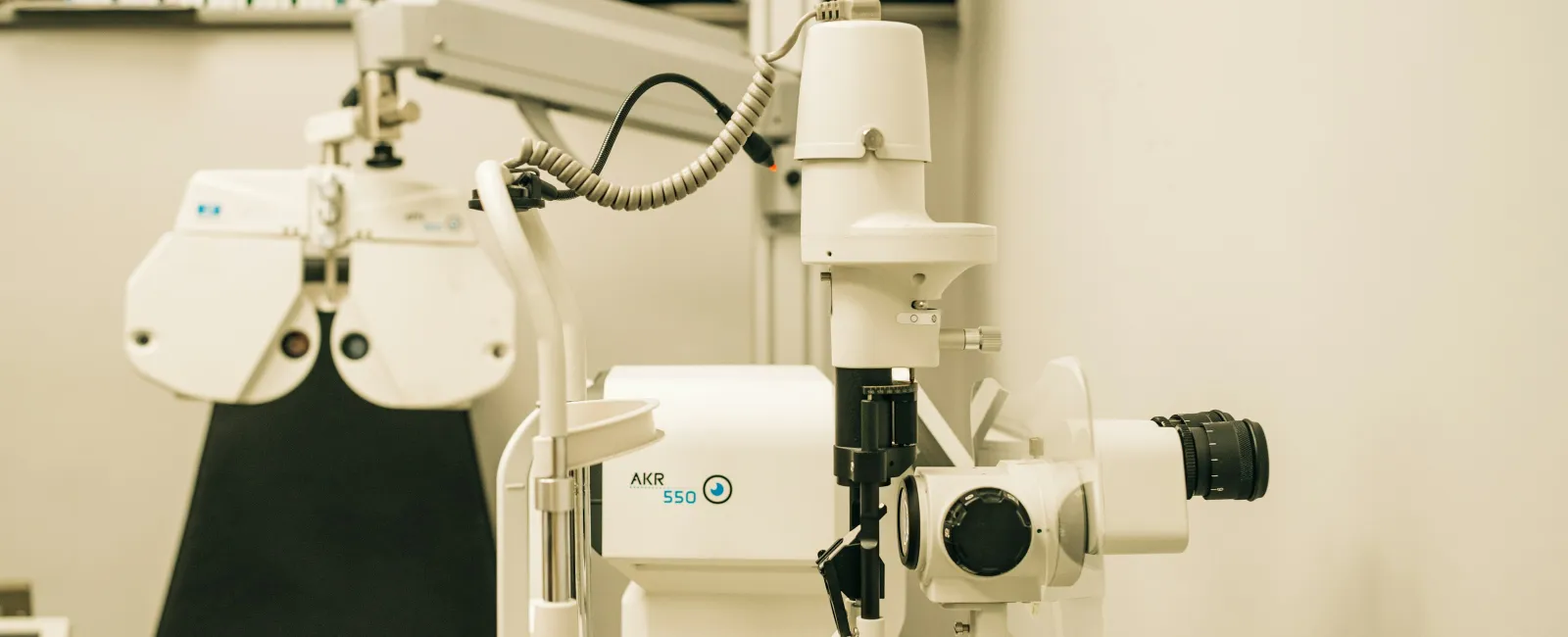 Close-up of modern ophthalmology equipment and eye exam chair in a well-lit medical clinic room.
