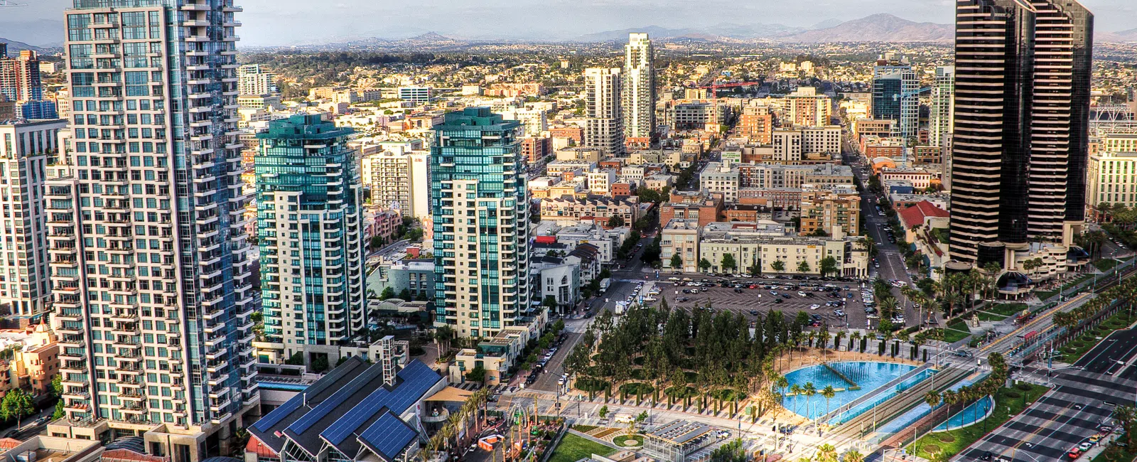Aerial view of a modern cityscape with high-rise buildings, green parks, and clear skies during daytime.
