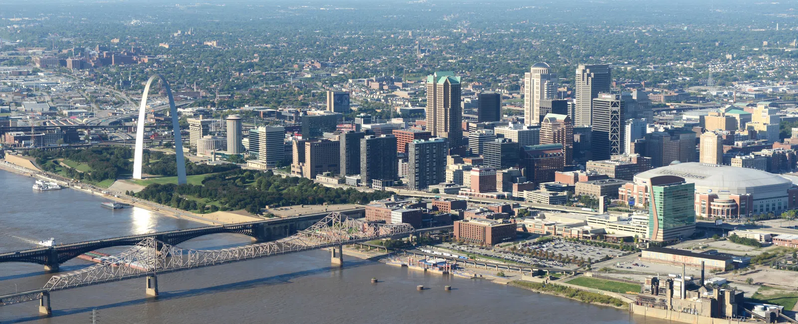 Aerial view of St. Louis skyline with Gateway Arch, Mississippi River, bridges, and urban buildings on a clear day
