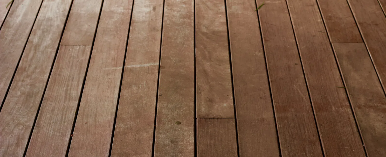 Close-up of weathered wooden floorboards with visible grain and slight discoloration in natural light.