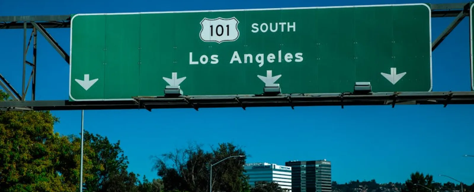 Highway 101 South road sign directing to Los Angeles above a busy street with cars and city buildings in the background