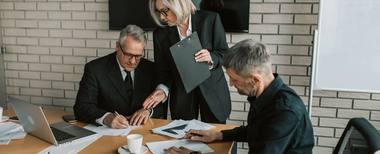 Three business professionals collaborating over documents in a modern office meeting room