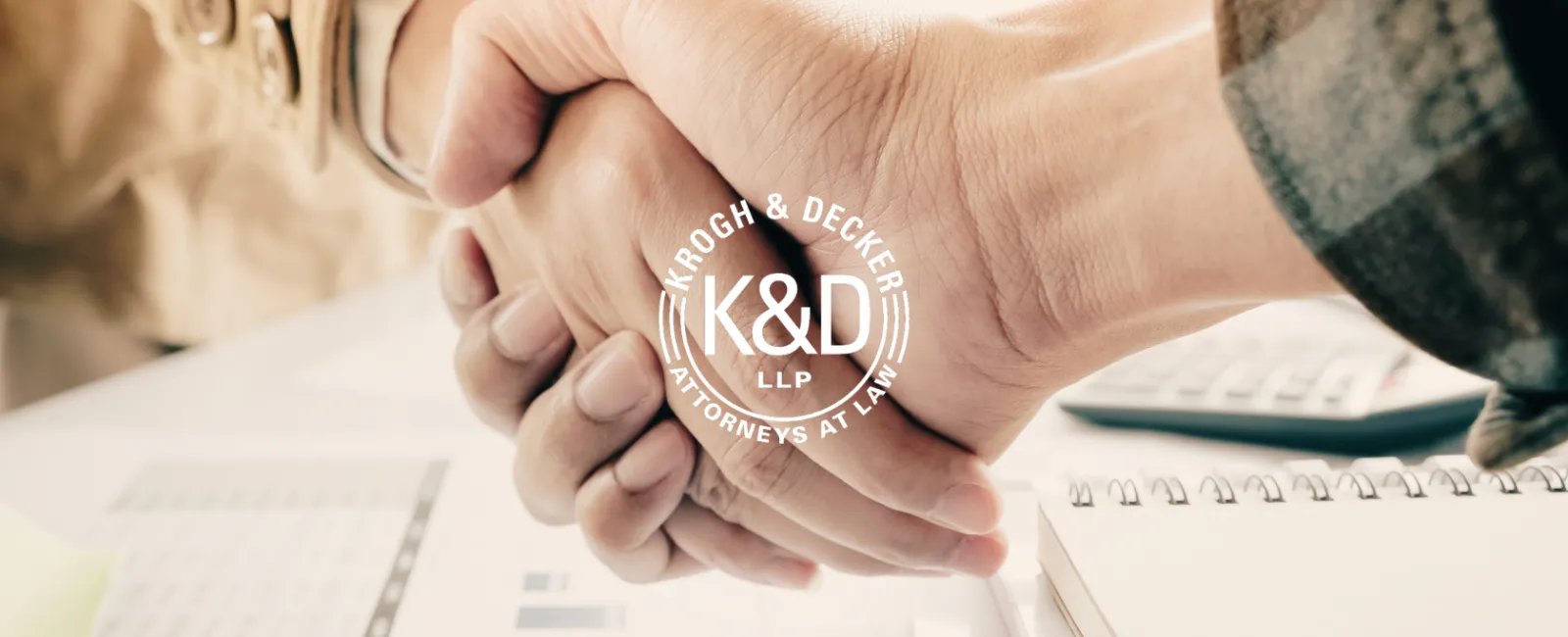 Two people shaking hands over office documents and notepad symbolizing agreement and partnership.