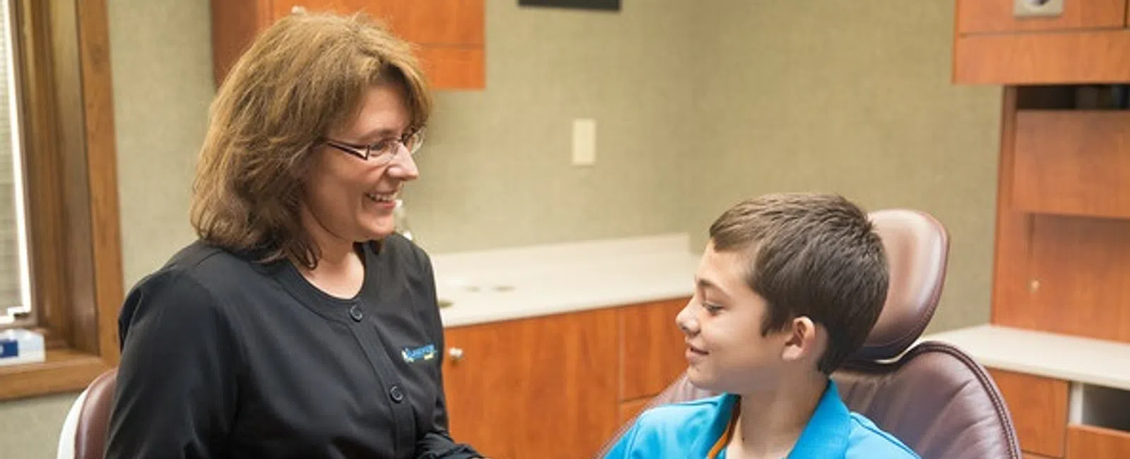 Dental hygienist showing a young boy how to brush teeth during National Dental Hygiene Month at Lakeview Dental.