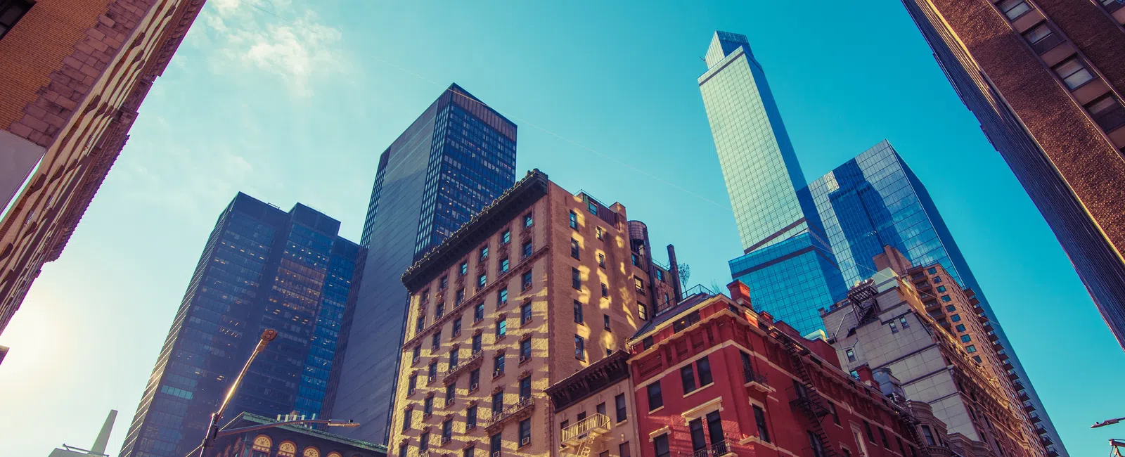 Downtown cityscape with a mix of modern skyscrapers and historic brick buildings under a clear blue sky.