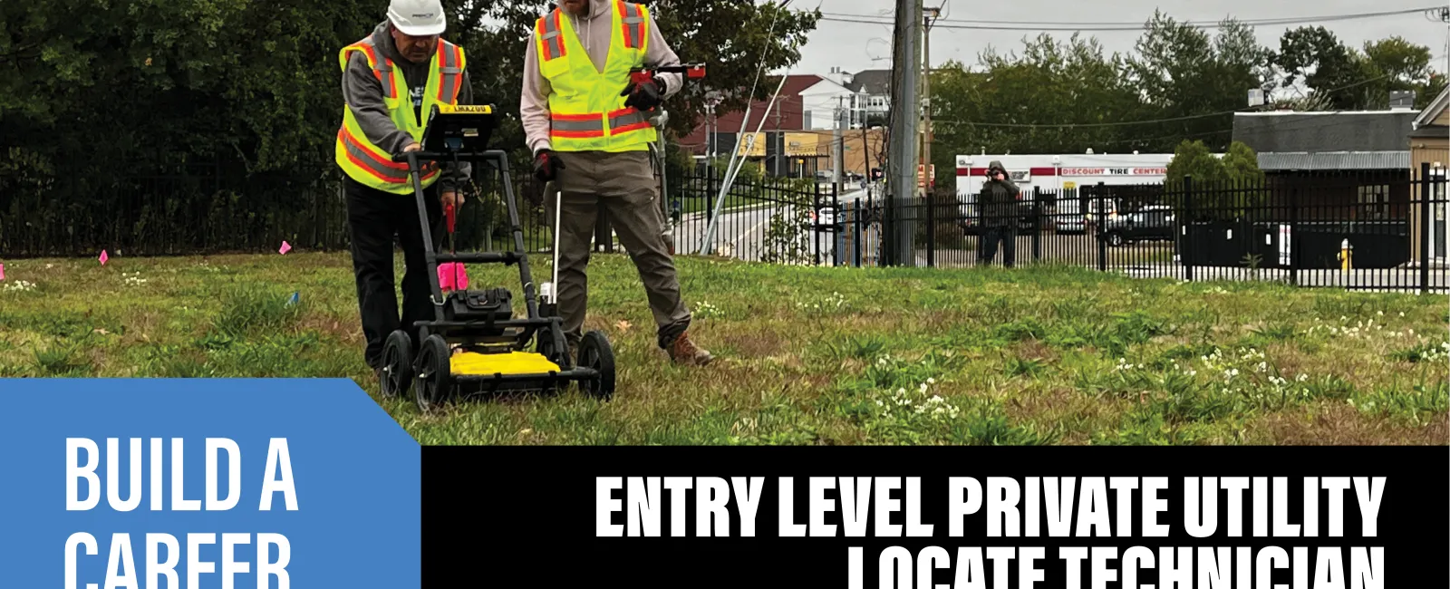 a couple of men wearing safety vests and standing next to a lawn mower