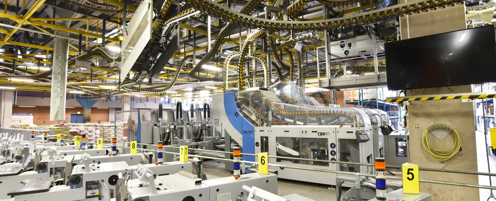 Modern industrial factory interior with automated machinery and conveyor belts under bright overhead lighting.