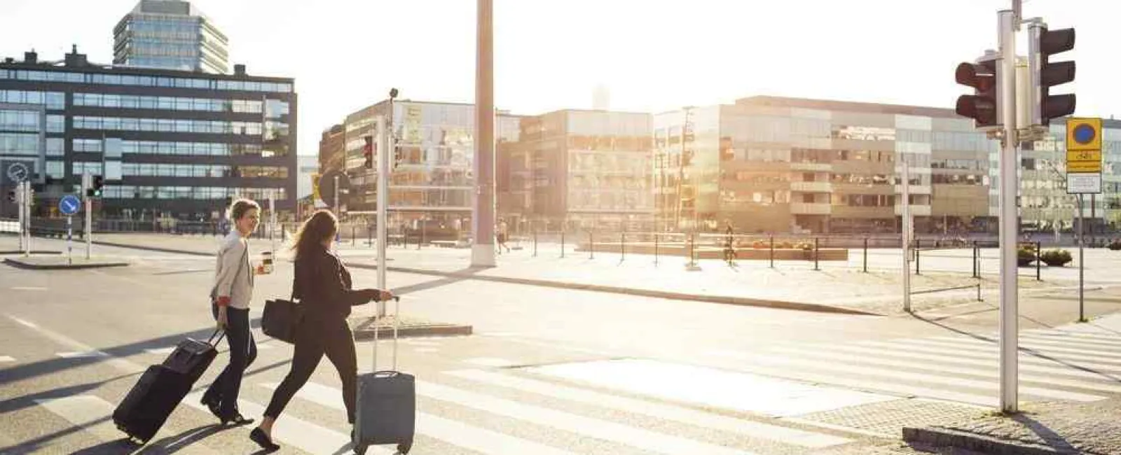 people with luggage walking across a crosswalk