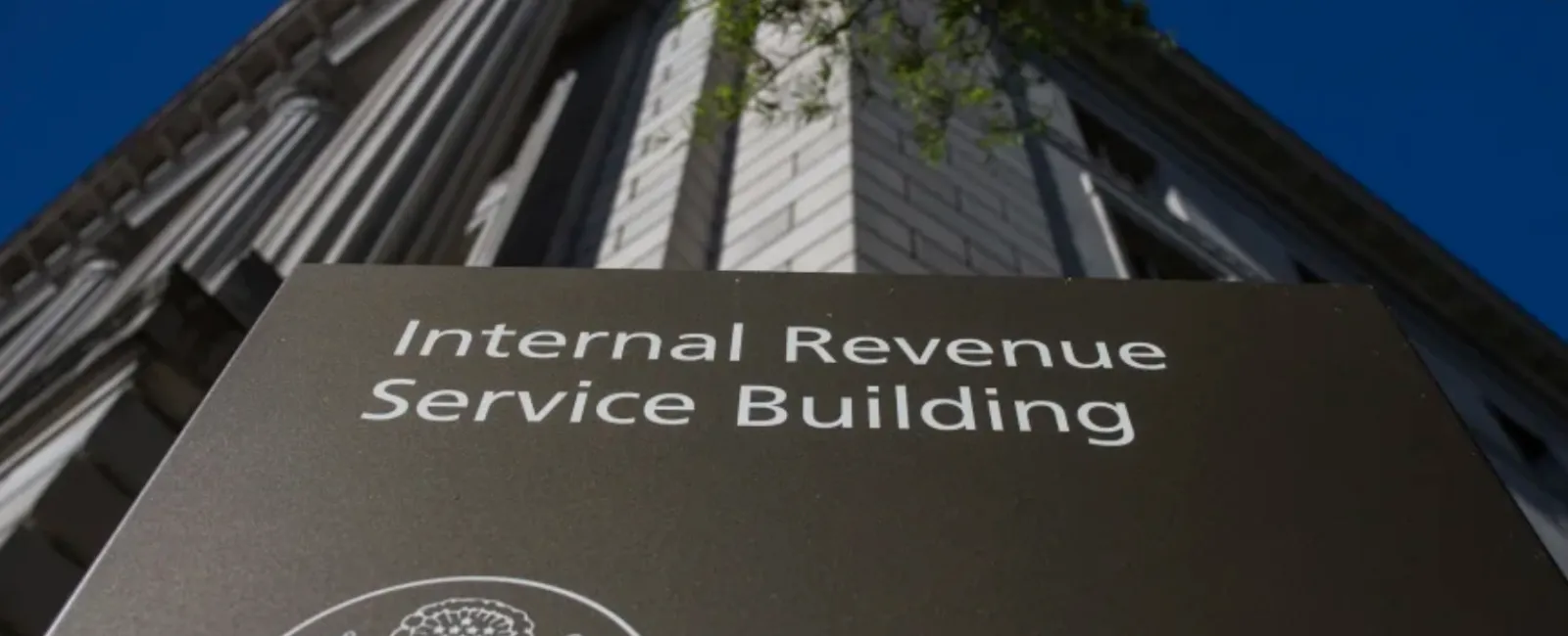 Sign for the Internal Revenue Service Building with a classical architecture background and clear blue sky.