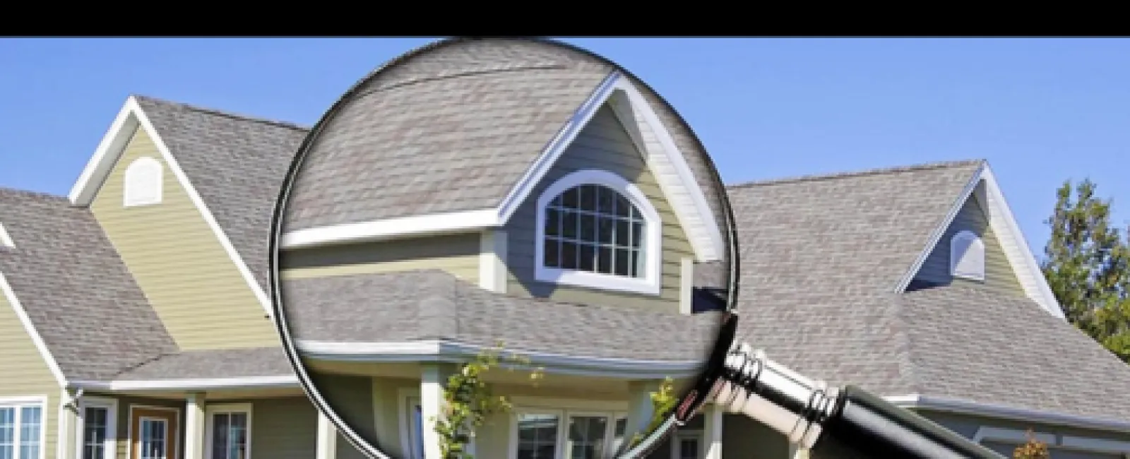 Magnifying glass focusing on a house roof and windows with clear blue sky in background for home inspection