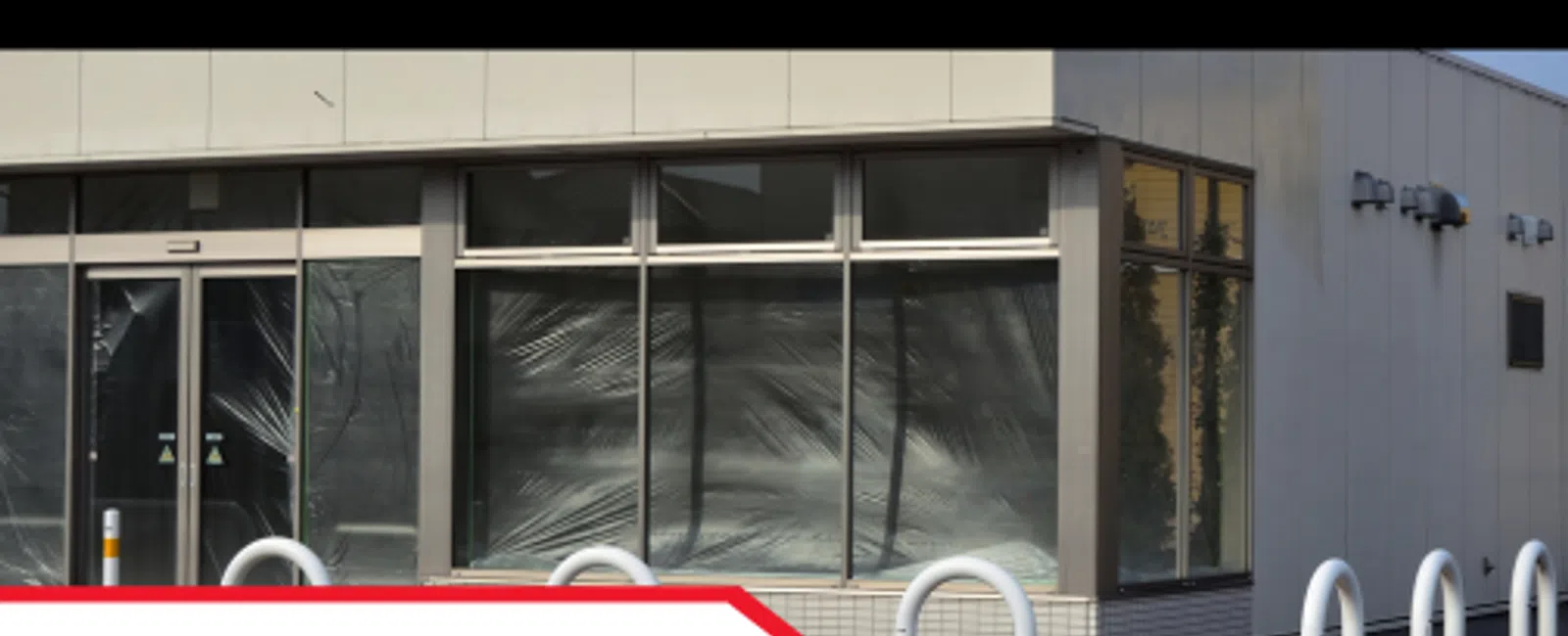 Empty storefront in a multi-tenant commercial building with safety bollards outside for property inspections.