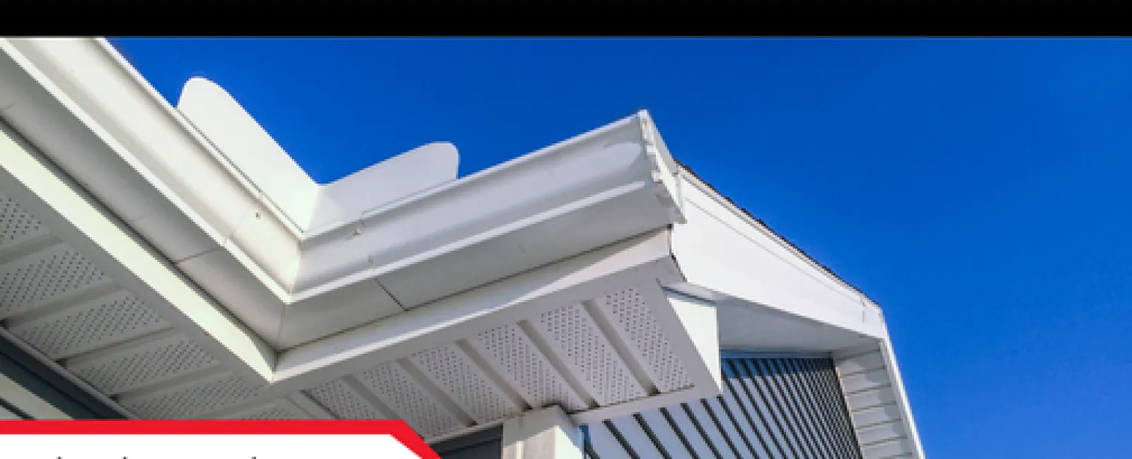 Close-up of a house's white siding and roof edge under clear blue sky, with siding inspection label.