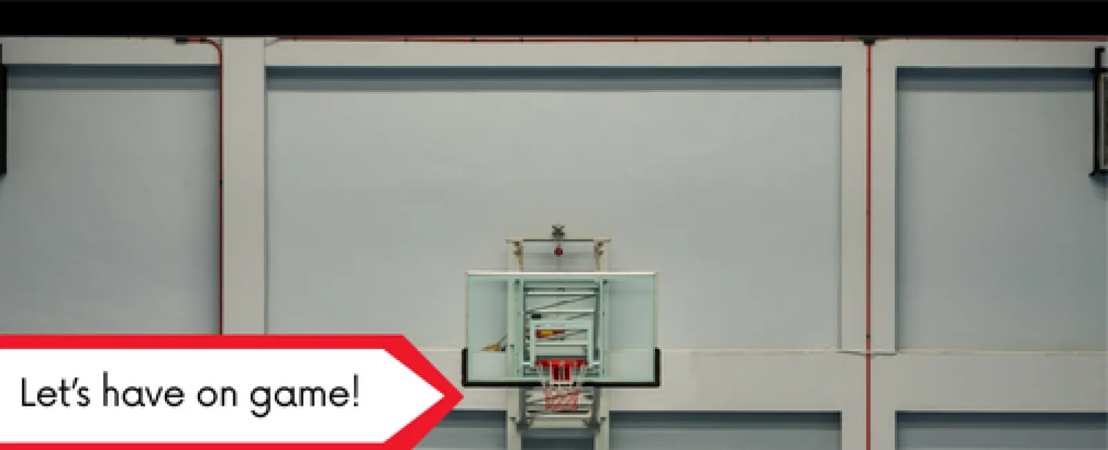 Indoor basketball hoop with a glass backboard mounted on a gym wall, accompanied by a motivational caption.
