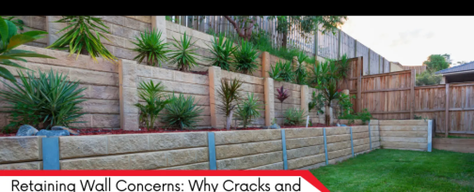 Modern tiered retaining wall with plants and green lawn in a residential backyard under clear sky