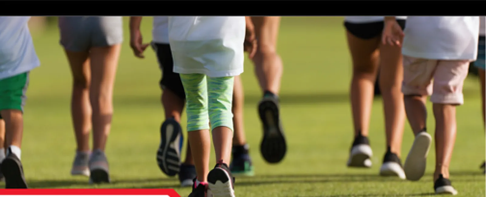 Close-up of people running barefoot and in shoes on grass during The Promise Race event.